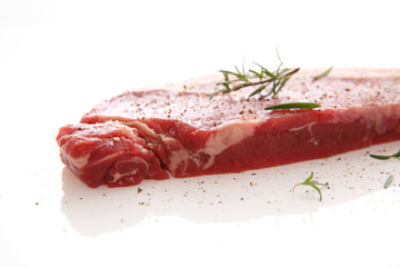 Fresh raw beef steak with pepper and rosemary isolated in white background