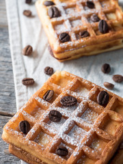 Soft Viennese Belgian waffles with powdered sugar and coffee beans on rustic wooden background