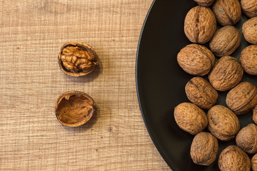 Walnuts on a black plate and on a wooden table