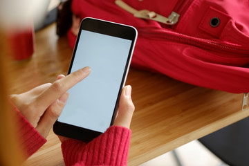 Mockup image of hand holding black mobile phone with blank white screen.