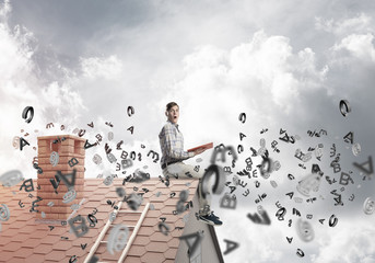 Man on brick roof reading book and symbols flying around