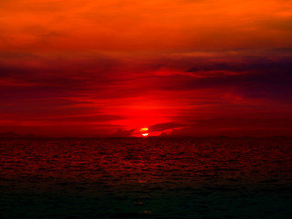 sunset last light of sun on horizontal line over red sky and ocean