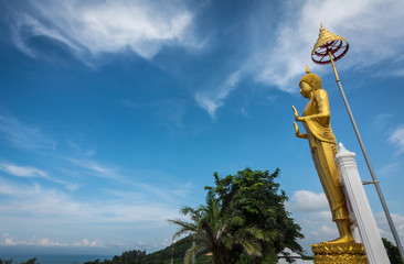 Golden Standing Buddha with bluesky in the background at Khungvimarn Viewpoint  Chanthaburi, Thailand.
