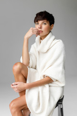 Young beautiful woman with short stylish haircut in elegant knitted dress posing sensually in...