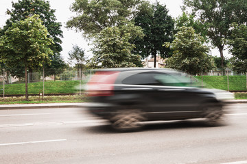 A black car at high speed crosses a pedestrian crossing, a motion blur effect