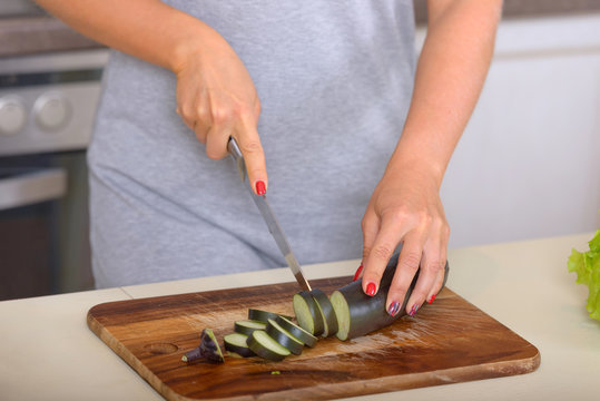 Woman cuts slices eggplant on cutting board