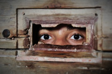 The two brown eyes of a woman in the hole of the ancient door