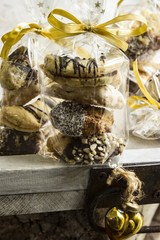 Mehrere Plätzchen in Cellophanbeutel mit goldfarbiger Schleife auf einem Holztablett