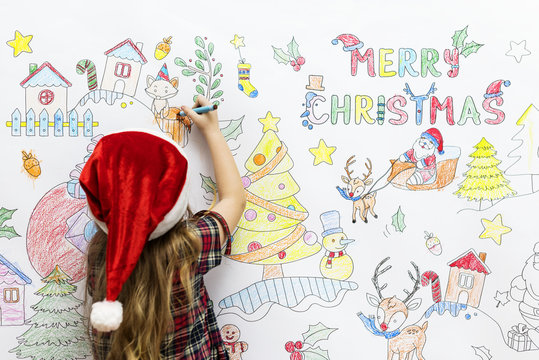Little girl drawing Christmas pictures on a white wall