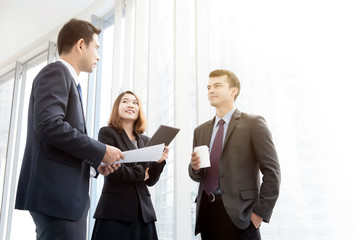 Business people standing at office building hallway talking during coffee break