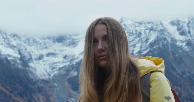 Beautiful Caucasian female hipster hiker making a selfie or video call in front of Mont Blanc massif. 4K UHD RAW 60 FPS SLO MO