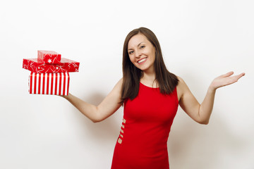 Beautiful caucasian young happy woman dressed in red dress and Christmas hat spreading hands holding gift boxes on white background. Santa girl with present isolated. New Year holiday 2018 concept
