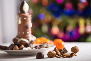 Chocolate and nuts on table on background Christmas tree