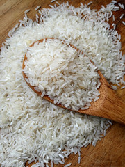 Heap of Jasmine Raw rice in wooden spoon on wooden table surface. Top view with selective focus
