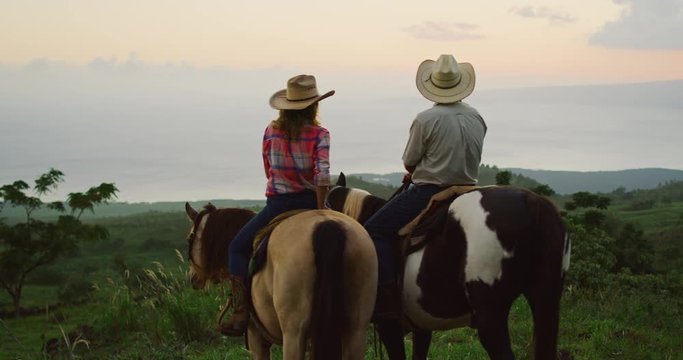 Couple horseback riding together at sunset