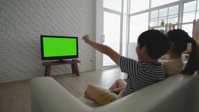 Boy and girl watching Television with green screen.