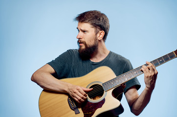 Man with a beard on a blue background playing the guitar, emotions, musical instruments