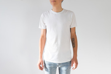 Obraz premium Front view or face side of young hipster millennial man, skinny and fit with arm tattoos, natural handsome beauty in white simple mockup tshirt from organic cotton