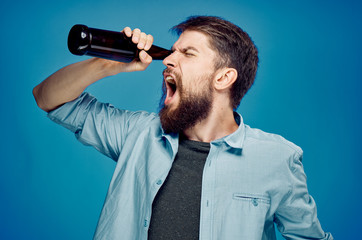 Fototapeta na wymiar Man with a beard on a blue background drinking beer, alcohol
