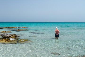 Old man standing in the middle of the sea