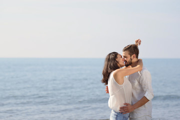 Romantic young couple on the beach kissing.