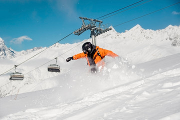Fototapeta na wymiar Snowboarder in colorful sportswear riding down the snow hill