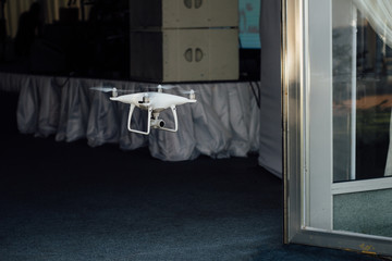 Drone quad copter spy flies through the door of the banquet hall of the cafe.