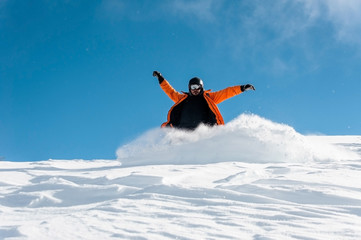 Naklejka na ściany i meble Male snowboarder in orange sportswear riding down the powder snow hill