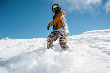 Naklejka na ściany i meble Portrait of snowboarder in sportswear standing on the snow hill