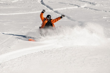 Snowboarder in orange sportswear riding on the snow slope