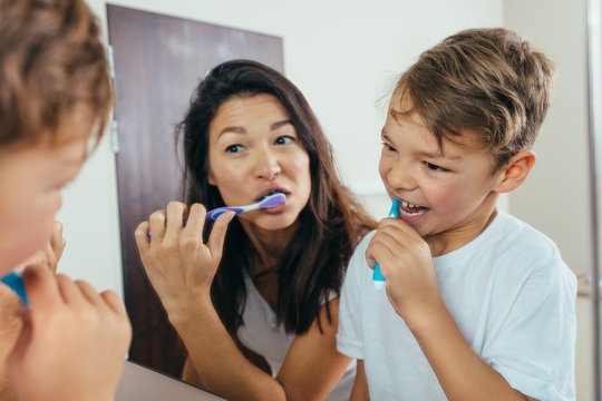 Mother and son brushing teeth in bathroom
