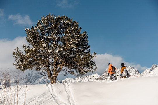 Couple of snowboarders in sportswear climbing the mountain