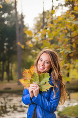 Cute smiley girl holding leafs in the nature.