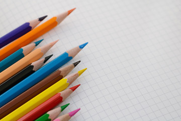 Top view of colored pencils on checkered paper. Copy space.