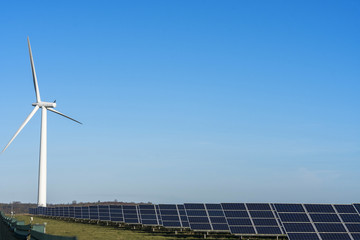 Solar panels and a wind turbine on a clear blue sky day in the English countryside
