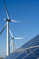 Solar panels and wind turbine on a clear blue sky day