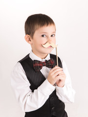 A boy with props mustache in studio over grey background