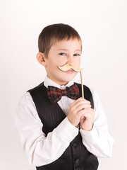 A boy with props mustache in studio over grey background