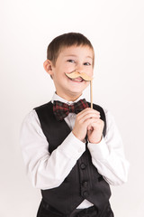A boy with props mustache in studio over grey background