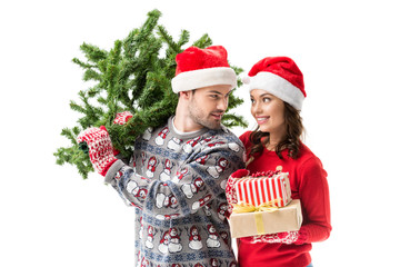 couple carrying christmas tree and gifts