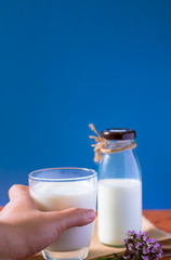 A glass of milk and bottle of milk on wooden table with blue background,healthy drink,high calcium for kid elderly and pregnant women.