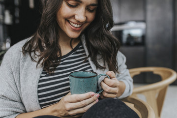 Junge Frau trinkt Kaffee oder Tee in einer Küche