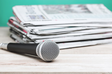 Microphone with newspaper on wooden table - announcement concept