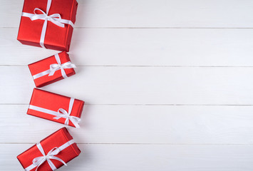 Obraz premium Red gift boxes with white ribbon on white wooden background, copy space. Holiday greeting card. Mothers day, birthday, Women's Day, mum's day, Valentine's day, Christmas, Wedding. Top view, flat lay