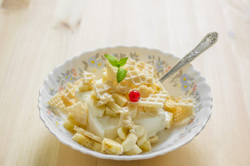 Vanilla ice cream in a plate with pieces of waffle and mint
