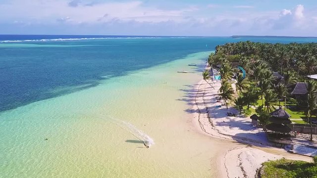 Aerial view of Kitesurfer cruising on empty blue water lagoon on tropical island