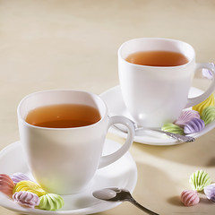 two white cups of tea with colorful meringue