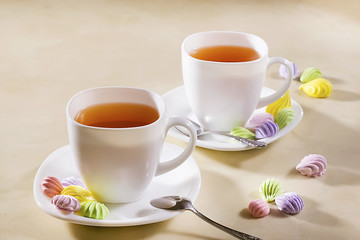 two white cups of tea with colorful meringue