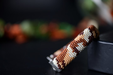 Camouflage bracelet made of seed beads on a dark background close up