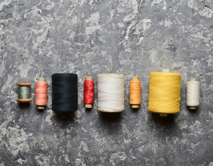 A group of multicolored skeins of thread on a gray concrete background. The concept of needlework....